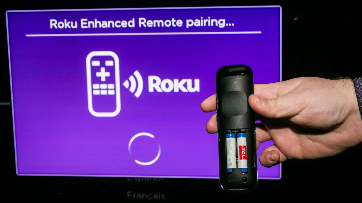 roku remote placed beside smart tv