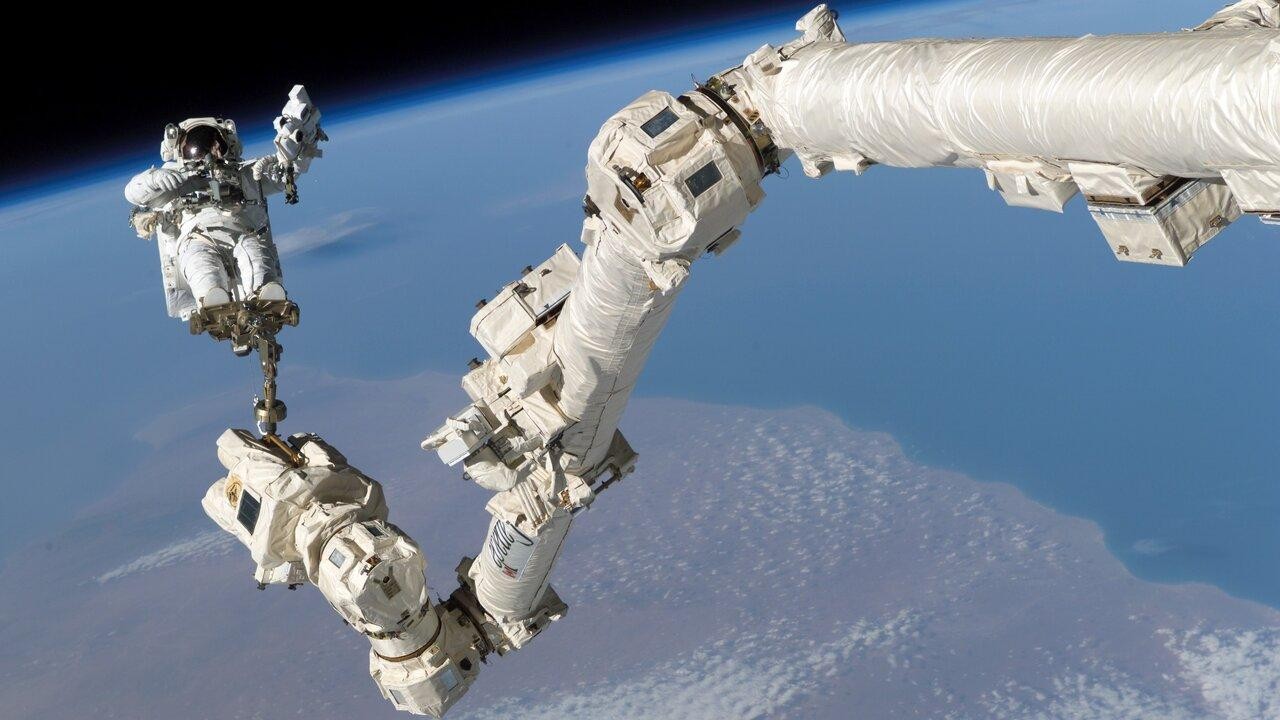 a space robotic arm helping astronot