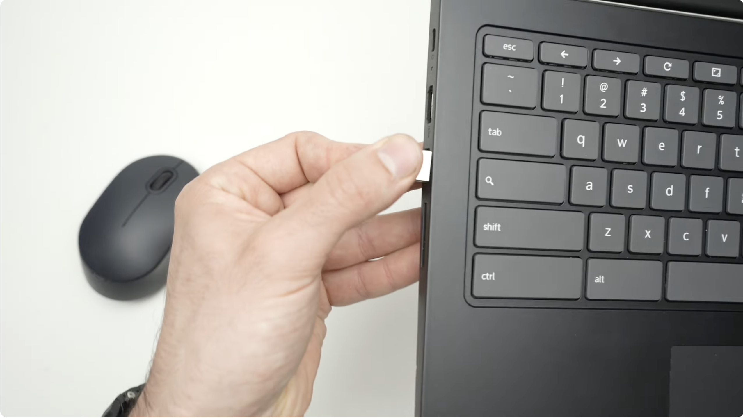 a picture of a hand inserting USB receiver into laptop