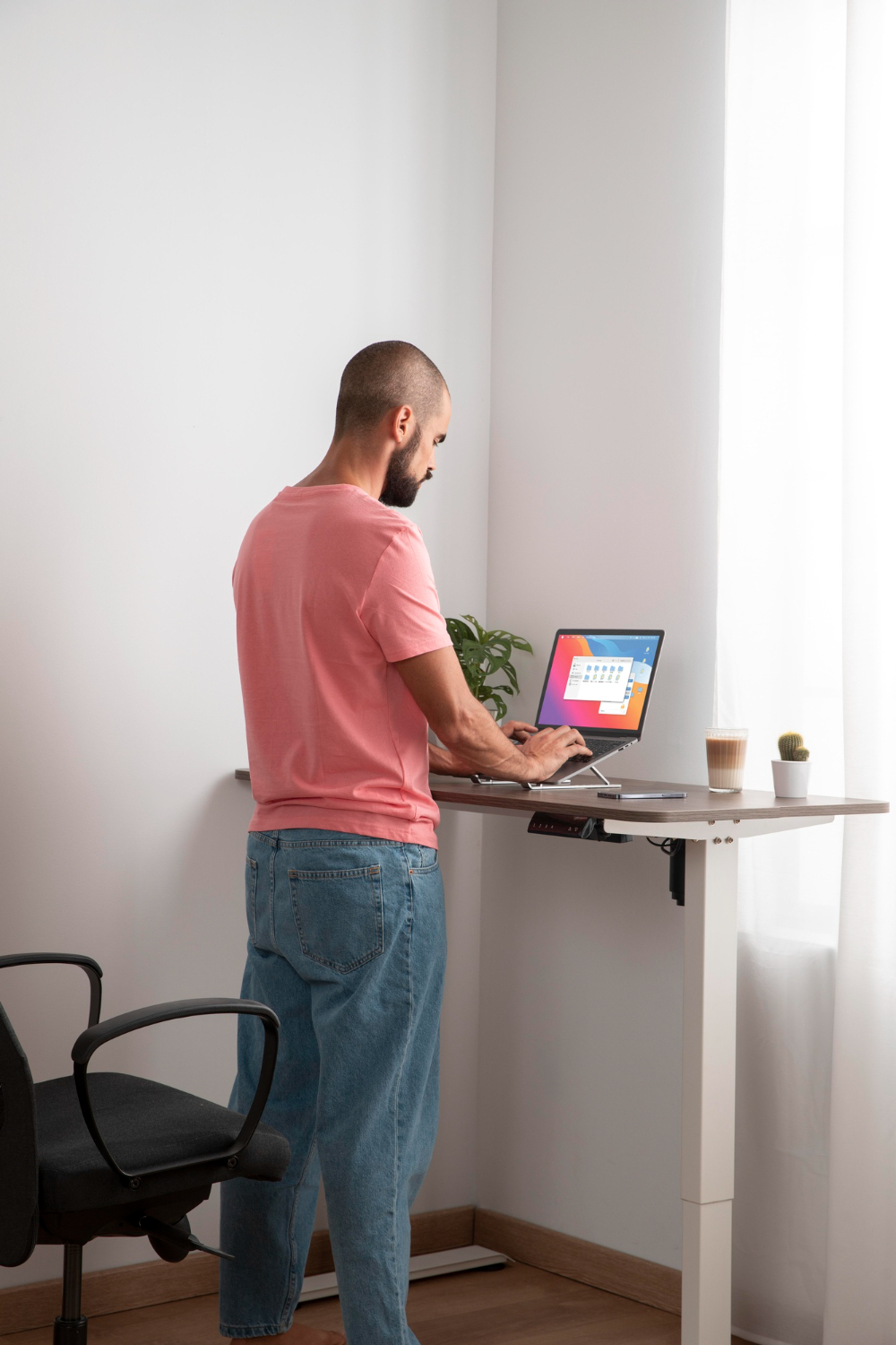 man in pink shirt standing and typing