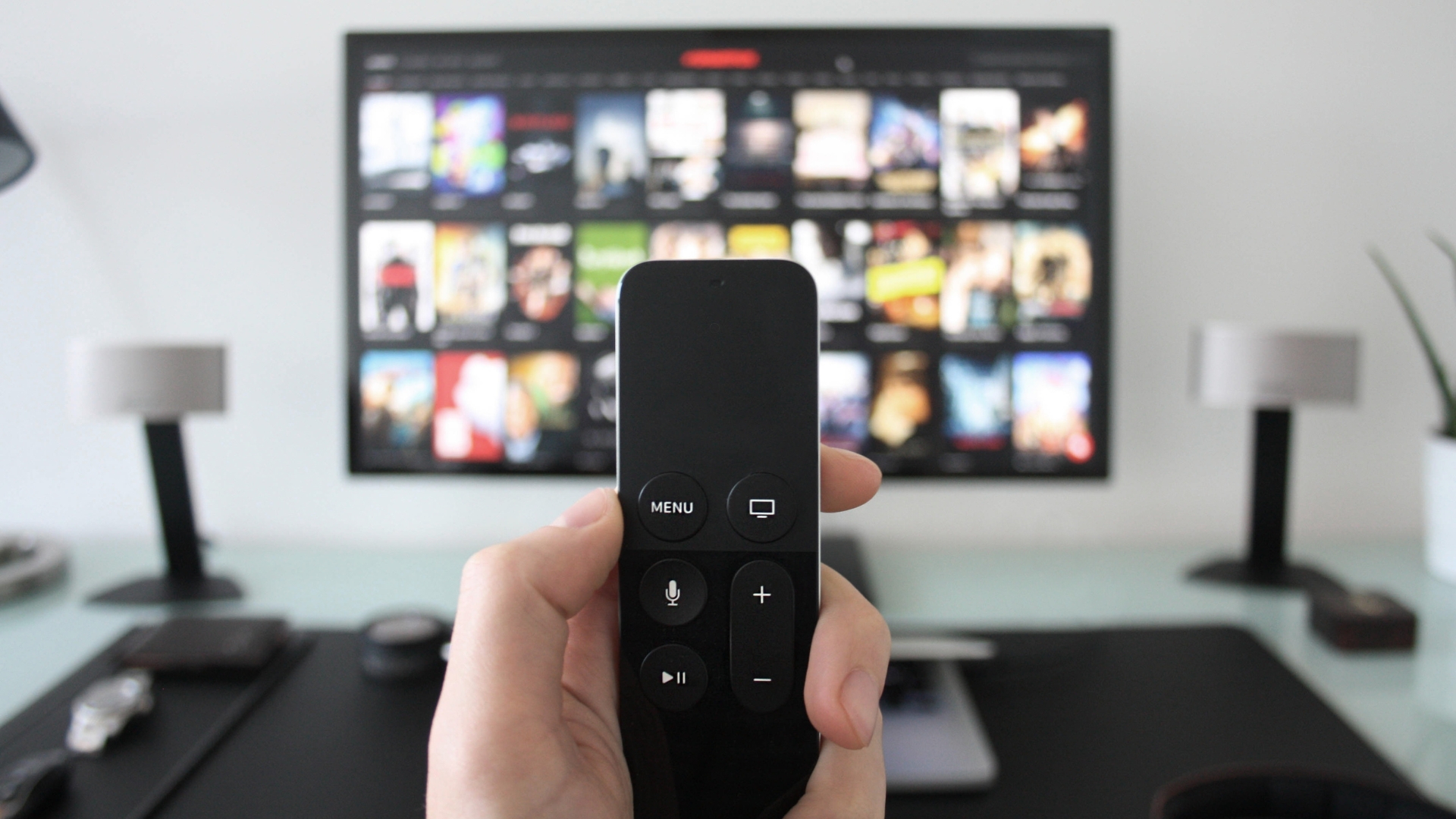 Picture of remote held up with tv behind