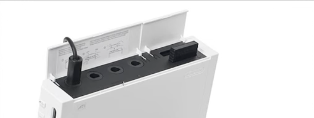 A GameCube controller being plugged into the top ports of an original Nintendo Wii console.