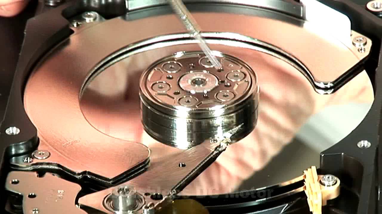 Close up of a hard disk drive platter and actuator arm inside an opened HDD casing