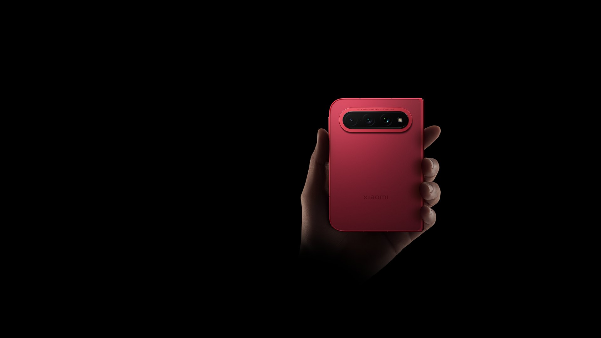 Hand holding the closed Xiaomi 18 Fold in red, rear camera module facing the viewer