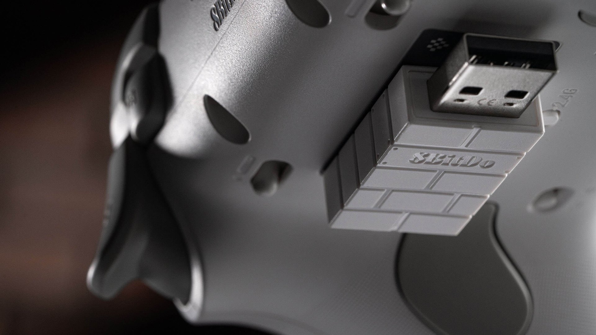 Close-up of the 2.4 GHz USB adapter seated in a recess on the back of a white controller