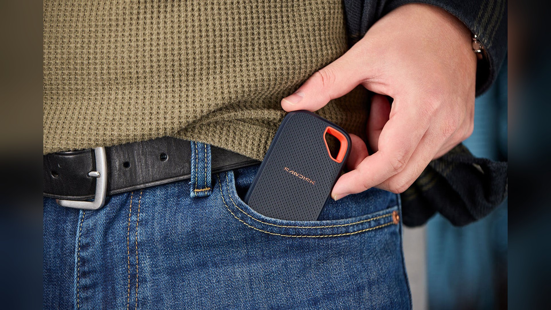 A hand slipping the SanDisk Extreme Portable SSD into a jeans pocket