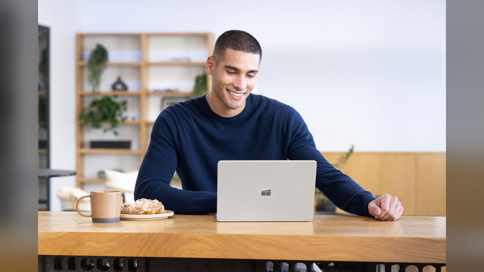 A man working on a 13-inch Surface Laptop at a cafe table